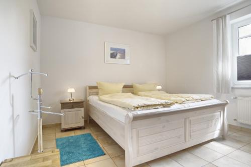 biała sypialnia z łóżkiem i oknem w obiekcie Vierkant FW 2 w Zingst
