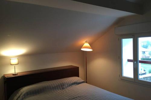 une chambre avec un lit et deux lampes et une fenêtre dans l'établissement APPARTEMENT BORDATCHOA, à Saint-Jean-de-Luz