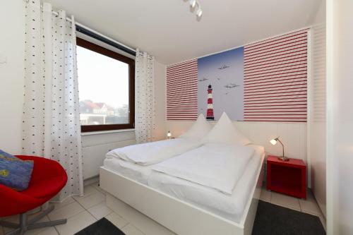 1 dormitorio con 1 cama blanca y 1 silla roja en Haus Bi de Wyk A1, en Wyk auf Föhr