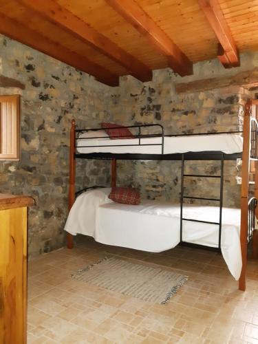 a bedroom with two bunk beds in a stone wall at La Granjita del río in Nava de Ordunte