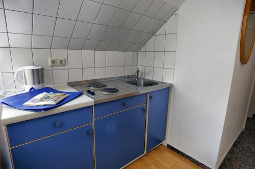 a small kitchen with a sink and blue cabinets at Altes Wasserwerk, App 5 in Zingst