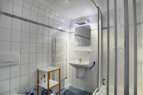 a white tiled bathroom with a sink and a mirror at Altes Wasserwerk, App 5 in Zingst