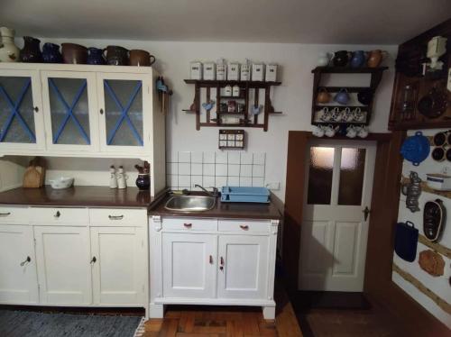 uma cozinha com armários brancos e um lavatório em Cafe Nostalgie čtyřlůžkový apartmán em Krásná Lípa