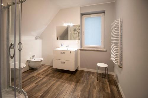 a white bathroom with a sink and a shower at Noclegi na Spokojnej in Miedziana Góra