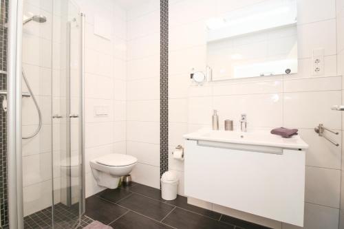 een witte badkamer met een toilet en een douche bij Atempause Greetsiel in Krummhörn