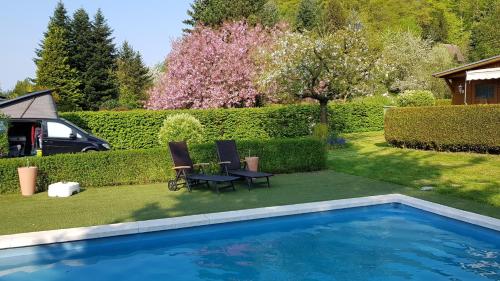 un patio con piscina y 2 sillas junto a un jardín en Poolhaus im Südharz, en Ilfeld