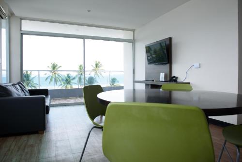 a living room with a table and green chairs at Puerto Azul Hotel in Puntarenas