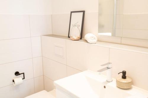 a white bathroom with a sink and a mirror at Apartment No2 in Stralsund
