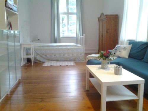 a living room with a blue couch and a baby crib at Ferienwohnung "Im Pfarrhaus Marlow" in Marlow