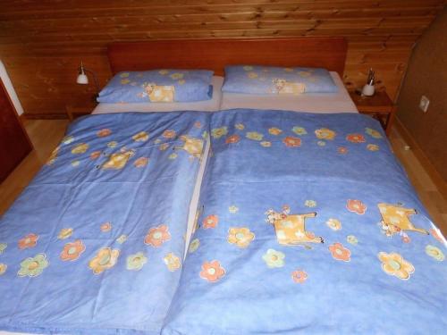 a bed with a blue comforter with animals on it at FeWo Vobbe in Dänischenhagen