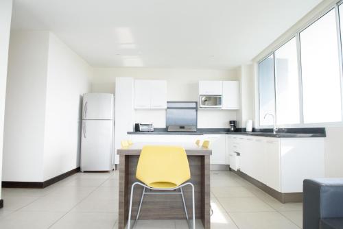 a kitchen with white cabinets and a yellow chair at Puerto Azul Hotel in Puntarenas