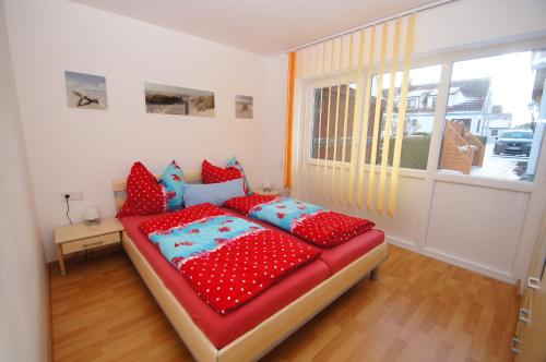 Schlafzimmer mit einem Bett mit roten und blauen Kissen in der Unterkunft Bungalow Timm in Kellenhusen