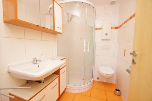 ein weißes Bad mit einem Waschbecken und einer Dusche in der Unterkunft Bungalow Timm in Kellenhusen