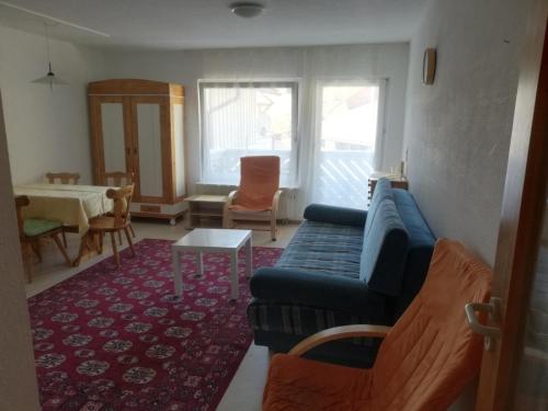 uma sala de estar com um sofá azul e uma mesa em Pension Goldmann - Ferienwohnung 3 em Schönau im Schwarzwald