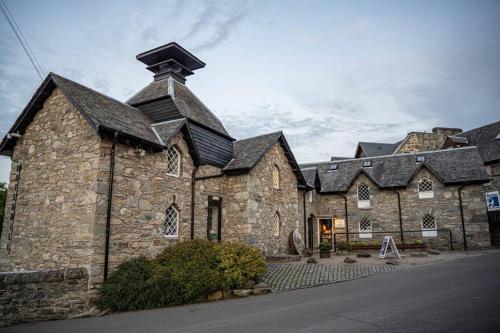 a large stone building with a black roof at Cozy Town Centre Apartment in Aberfeldy