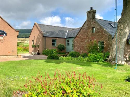 an old brick house with a basketball hoop in a yard at Coullie Stays in Auchenblae