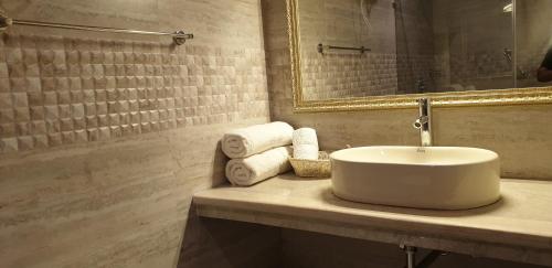 ein Badezimmer mit einem Waschbecken, einem Spiegel und Handtüchern in der Unterkunft Maple Leaf Hotel in Kharar