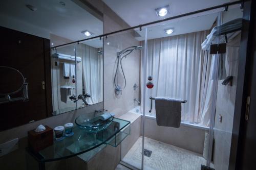 y baño con lavabo de cristal y ducha. en Seercuo International Hotel, en Songpan