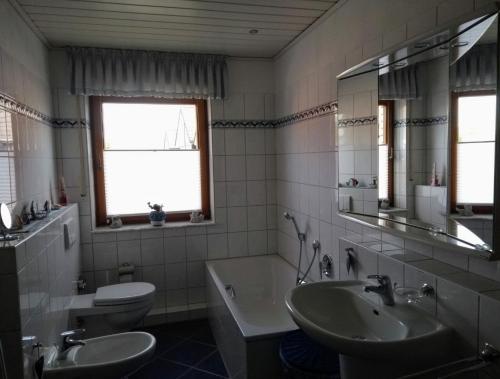 uma casa de banho com um lavatório, uma banheira e um WC. em Ferienwohnung-Lilienweg em Hilter