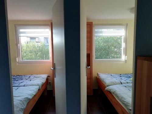 two beds in a room with two windows at Kleiner Bungalow im Grünen in Radeberg