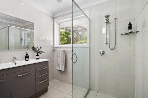 a bathroom with a glass shower and a sink at Killior'ra in Berambing