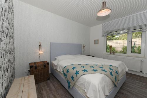 ein weißes Schlafzimmer mit einem Bett und einem Fenster in der Unterkunft Surfbude 01 in Utersum