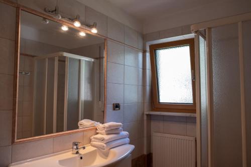 ein Badezimmer mit einem Waschbecken, einem Spiegel und Handtüchern in der Unterkunft Ferienwohnung im Haus Texel VII in Rabland