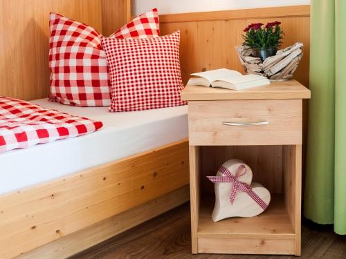 a bed with a wooden frame and a wooden drawer with a ribbon in a room at Riederstein Nr 8 in Bad Wiessee