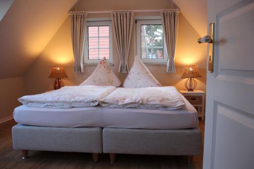 ein Bett mit weißer Bettwäsche und Kissen in einem Schlafzimmer in der Unterkunft Dörphuus Wohnung Dorfblick in Spiekeroog