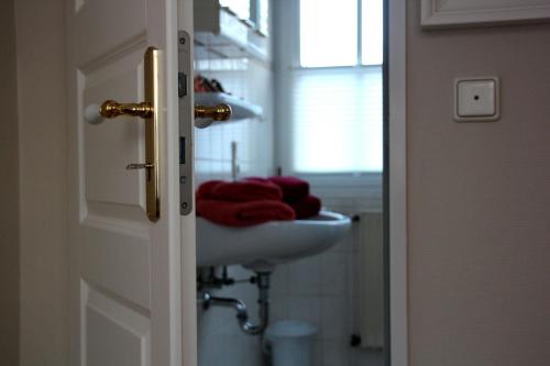 baño con lavabo y toalla roja en Dörphuus Wohnung Dorfblick, en Spiekeroog