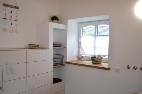 a white kitchen with a window and a window sill at Maritime Ferienwohnung auf Gut Bennewohld KP in Heide