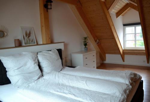 a bedroom with a bed with white sheets and a window at Maritime Ferienwohnung auf Gut Bennewohld KP in Heide