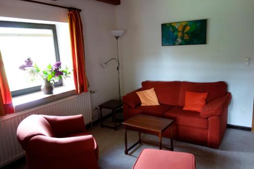 a living room with a red couch and a table at Ferienwohnung Neupert in Nübbel