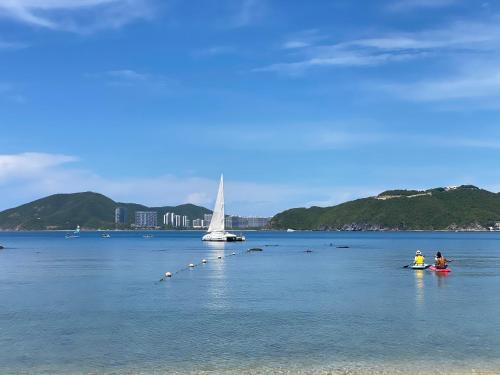 a couple of people in the water with a sail boat at Mandarin Oriental, Sanya in Sanya