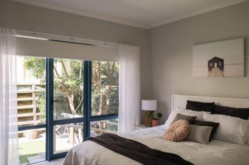 a bedroom with a bed and a large window at Corlette Shores. Dreamy Beachside Holiday Home. in Corlette