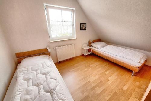 two beds in a small room with a window at Loca in Zingst