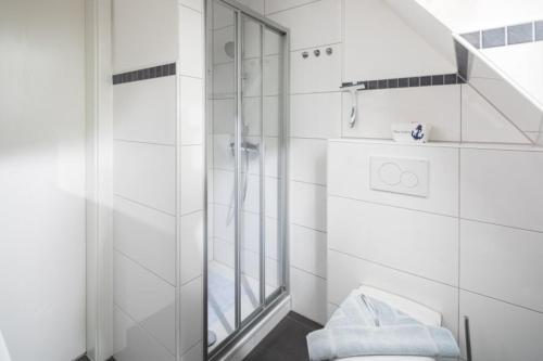 uma casa de banho branca com um chuveiro e um WC. em Captains Cabin em Norddeich