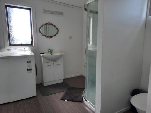 a bathroom with a glass shower and a sink at Central Holiday Home in Tauranga