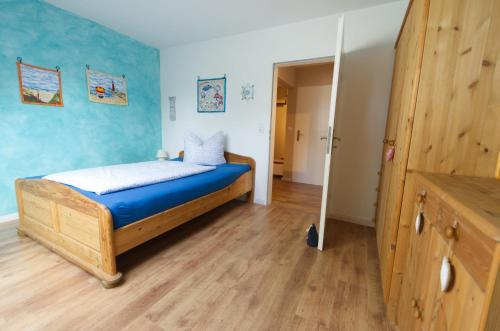 een slaapkamer met een bed met blauwe muren en houten vloeren bij Nordseebrise KrummhörnLoquard in Krummhörn