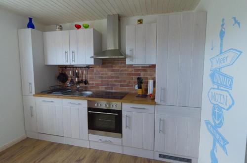 a kitchen with white cabinets and a brick wall at Nordseebrise KrummhörnLoquard in Krummhörn