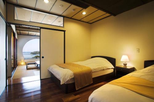 a bedroom with two beds and a view of the ocean at Ryoso Uminocho in Ise