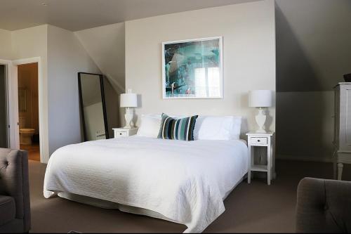 a bedroom with a white bed with two lamps and a mirror at Briarwood in Greytown