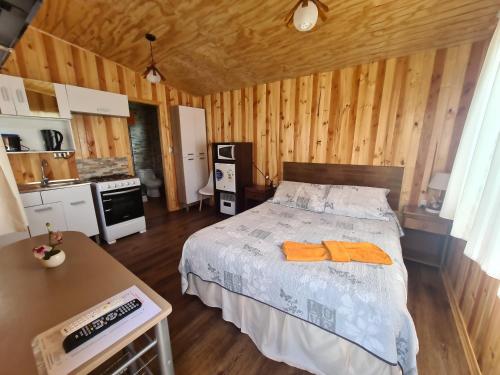 a bedroom with a bed with two orange towels on it at Cabañas Kompatzki in Ancud