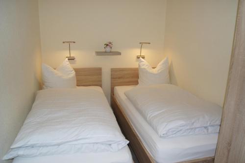 2 posti letto in una piccola stanza con lenzuola bianche di Ferienwohnung Glöckner a Burgtiefe auf Fehmarn 