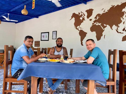 three men sitting at a table eating food at Sapphire Garden Hotel in Habarana