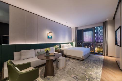 a hotel room with a bed and a couch and a table at Novotel Xian Xixian in Xi'an