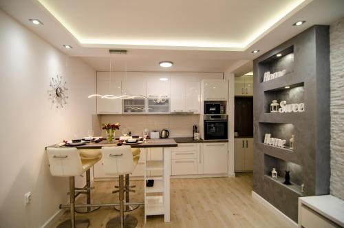 una cocina con armarios blancos y una isla con taburetes. en Apartman MDB LUX, en Subotica
