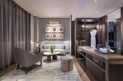 a living room with a desk and a chair and a couch at Novotel Xian Xixian in Xi'an