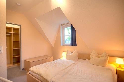 um quarto com uma cama branca e uma janela em Am Deich 16 em Zingst