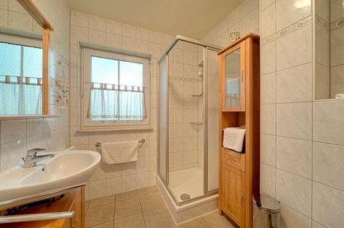 uma casa de banho branca com um lavatório e um chuveiro em Am Deich 16 em Zingst